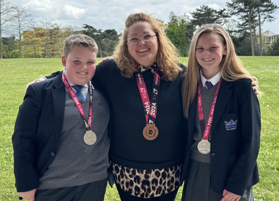 Two students and a staff member posing with their various running medals