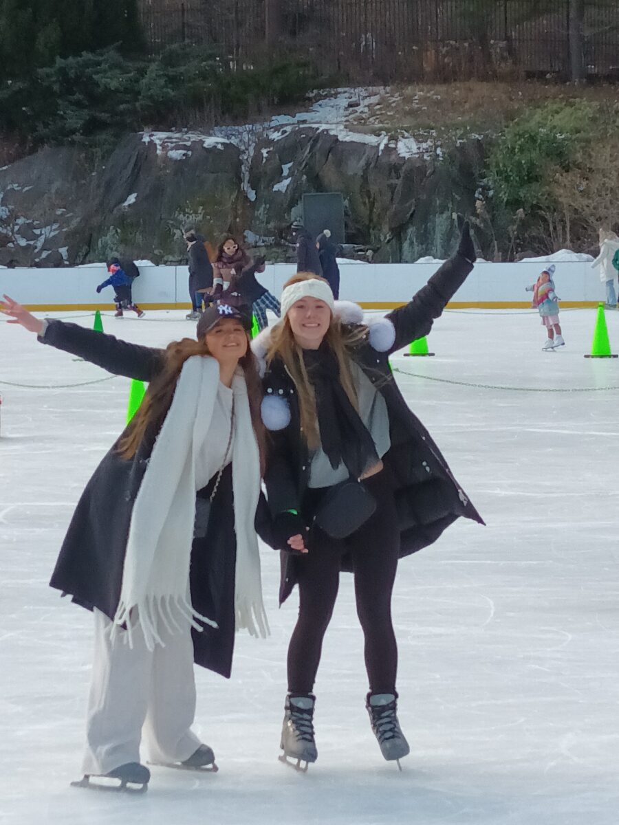 Two students with their arms in the air ice skating