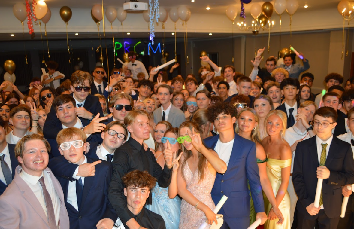 Year 11 pupils, dressed in suits and dresses, pose for a photo at their school prom. The Room also has balloons and decorations