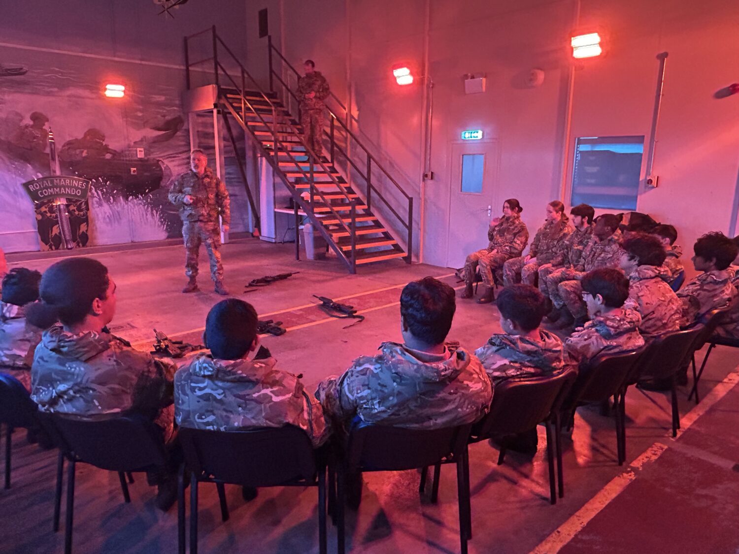 cadets receiving a talk from an officer. Guns a pictured on the floor