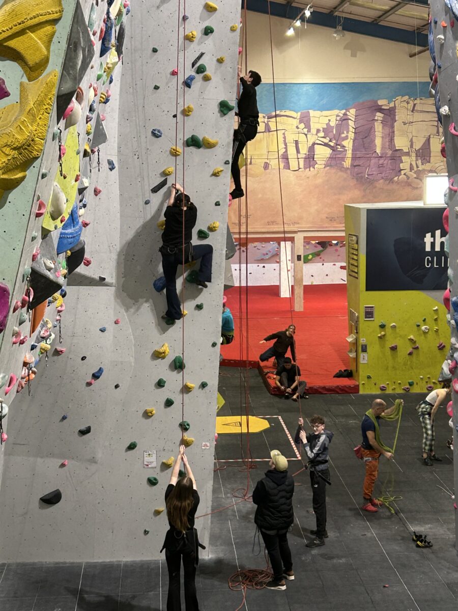 Two people on a climbing wall while others look on