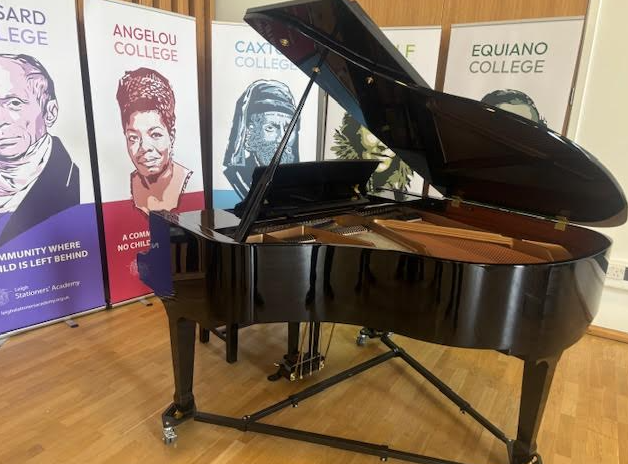 Picture of a black baby grand piano with school banners behind it