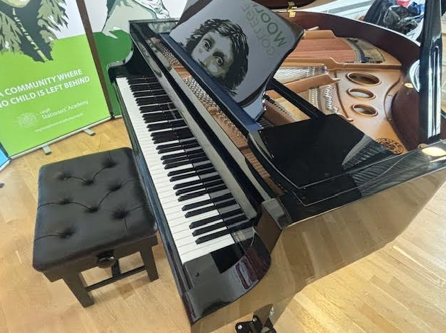 A close up of a baby grand piano, showing the pianos keys and a stall