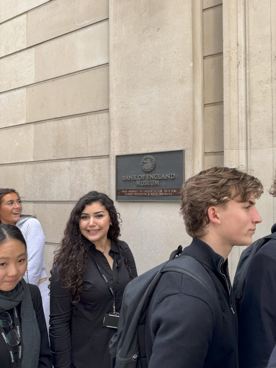 Students waiting in line outside the museum entrance; one female student smiles toward the camera.