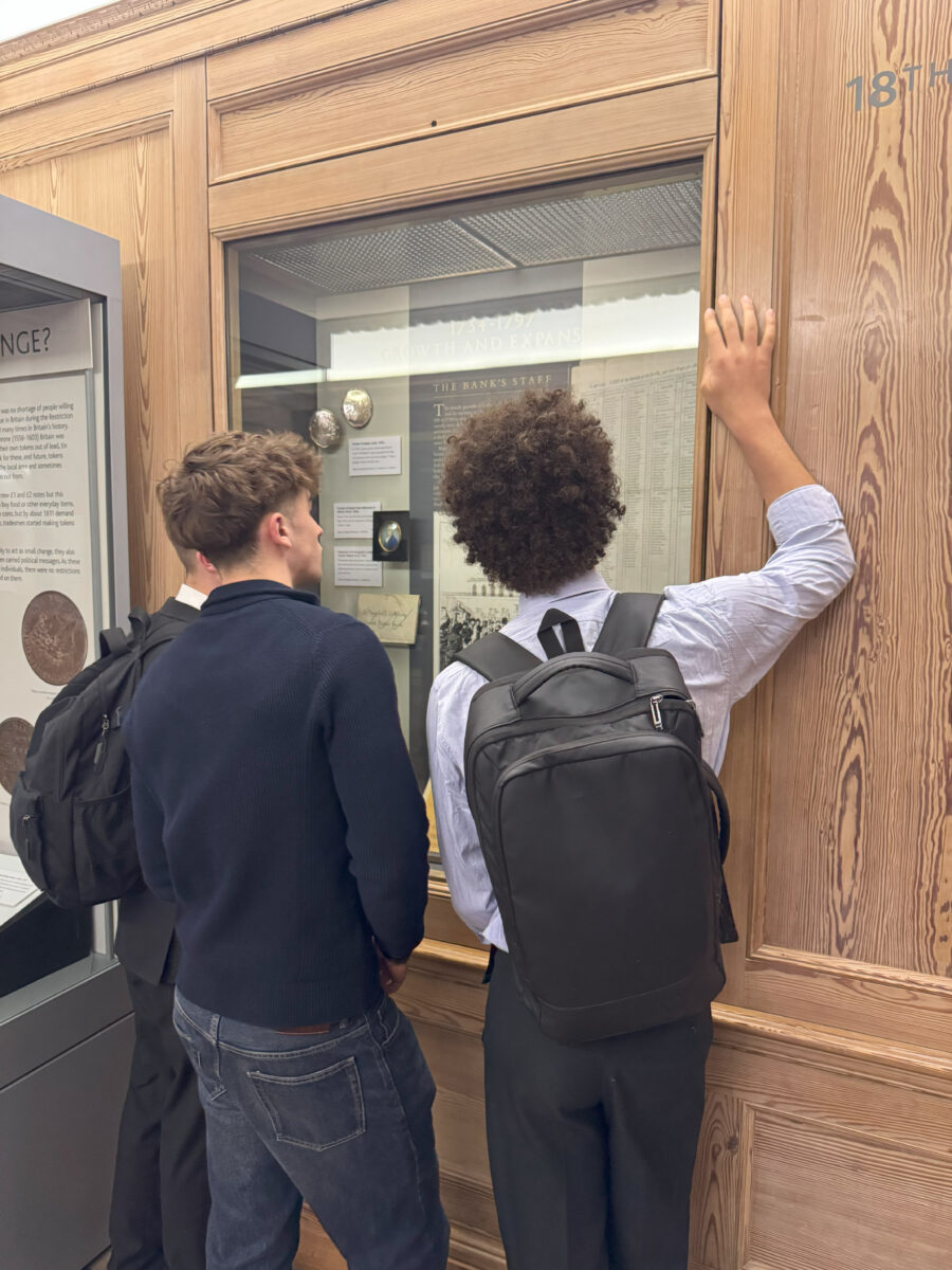 Two students look closely at an 18th-century "Growth and Expansion" exhibit housed in a wooden display case.