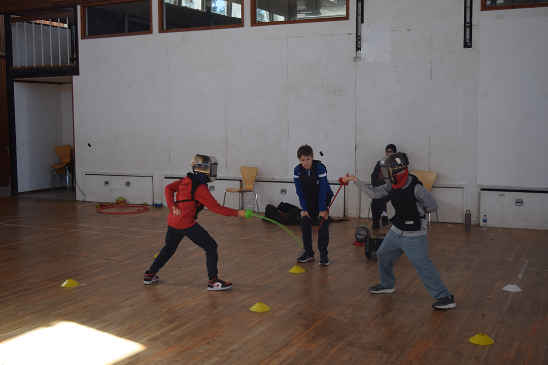 Two children trying the sport fencing in a gym hall