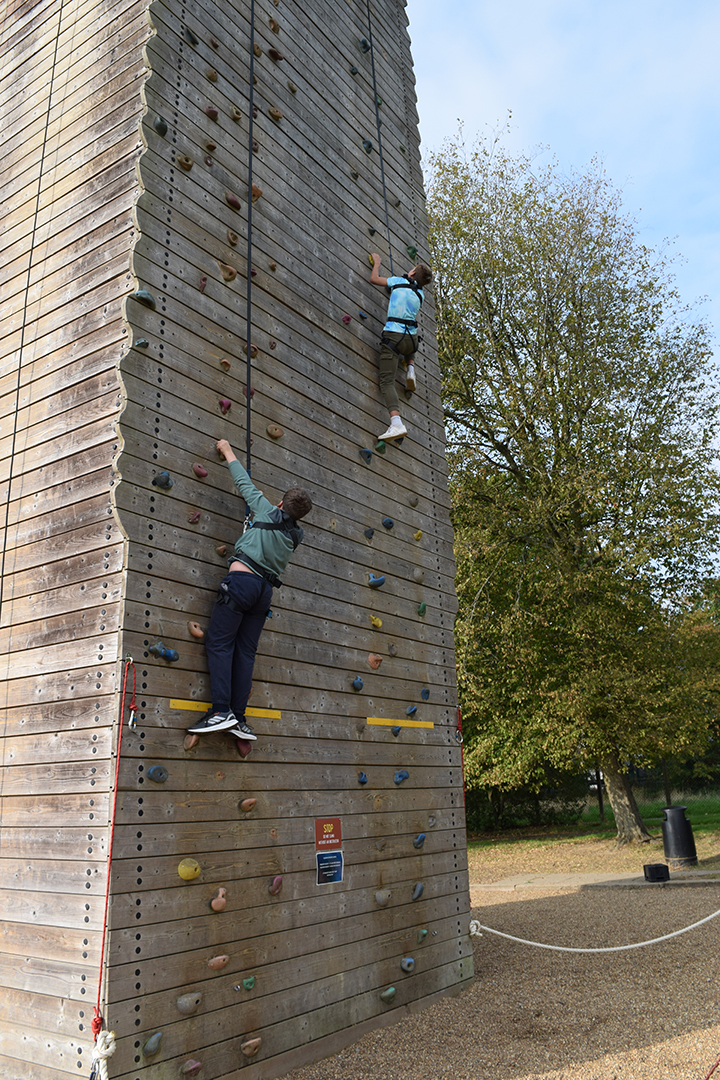 Two children on a wooden climbing wall. In an outdoor setting